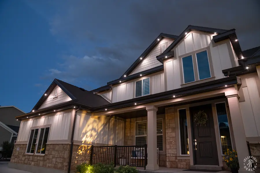 Two-story home at dusk with warm white Jellyfish lights along the roofline