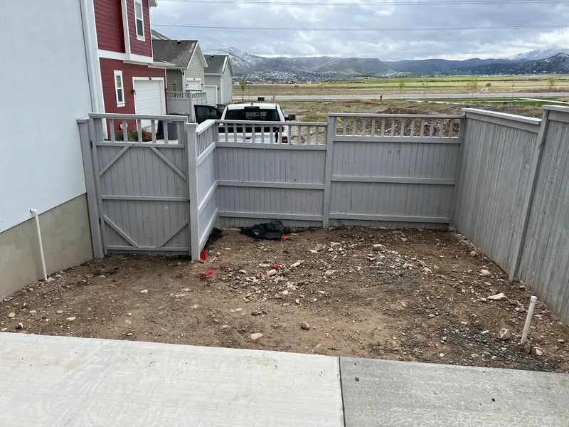 Fenced backyard with bare soil, cleared and ready for a new landscape